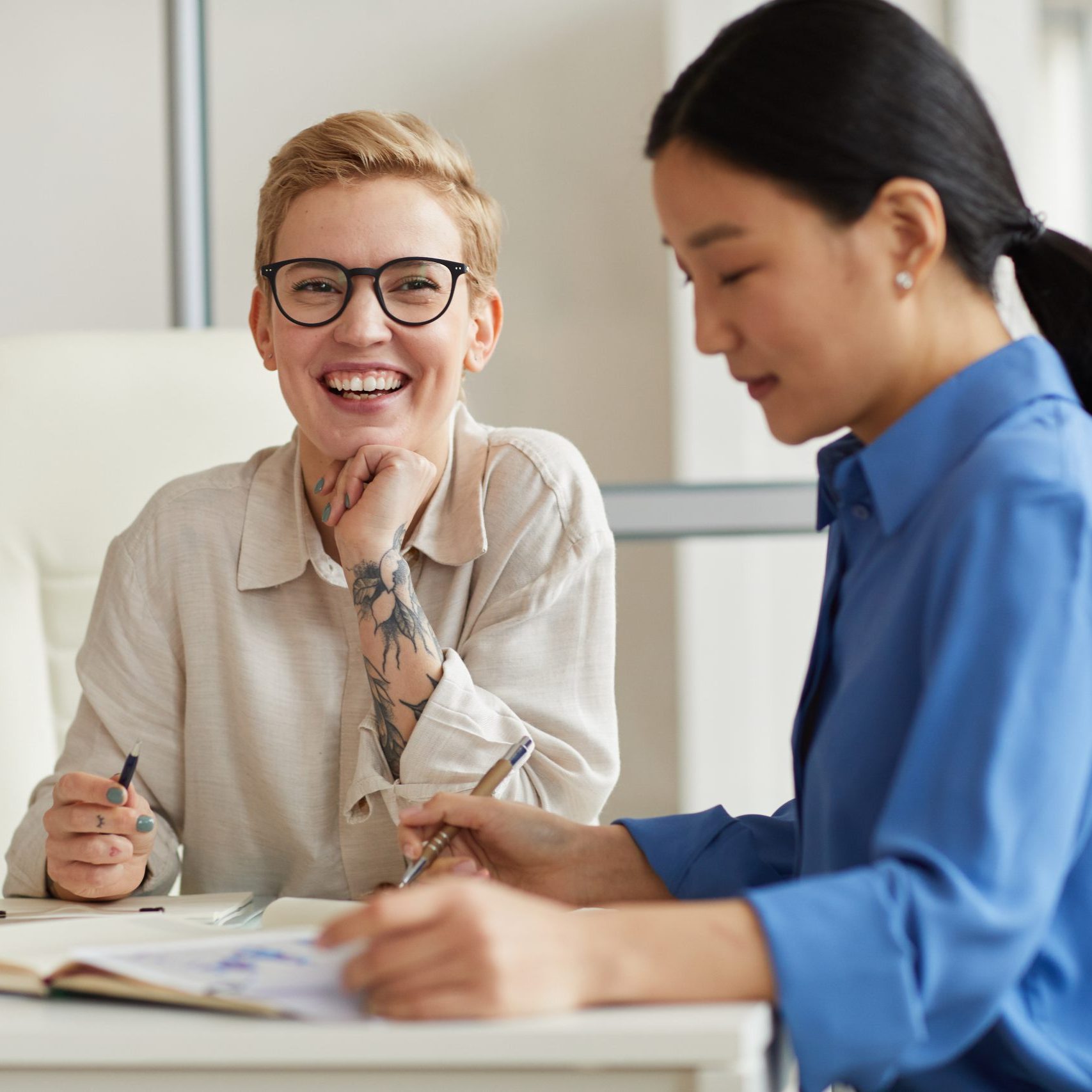 Two cheerful businesswomen enjoying work in office, copy space